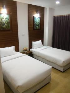 南邦南邦SR酒店的配有白色床单的酒店客房内的两张床