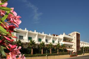 托雷瓦多Cala Saracena Resort的一座白色的建筑,前面有棕榈树