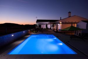 蒙萨拉什Monte Farropo的夜晚的蓝色游泳池与房子