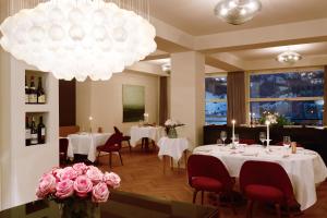 阿德尔博登Bellevue Parkhotel & Spa - Relais & Châteaux的餐厅设有白色桌子、粉红色的鲜花和吊灯