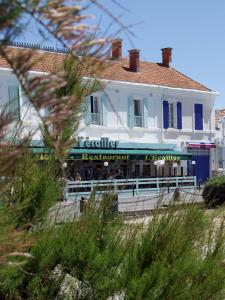 拉康提内勒Hôtel L'Ecailler的海滩上一座白色建筑,设有餐厅
