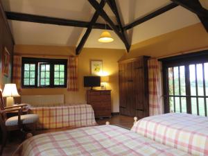 克雷迪顿Combe Lancey Farmhouse B&B的一间卧室设有两张床、一台电视和窗户。
