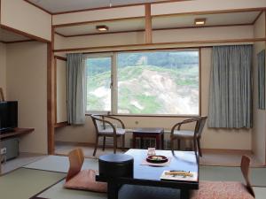 嬬恋村Manza Juraku All-inclusive Hotel的客厅配有桌椅和大窗户