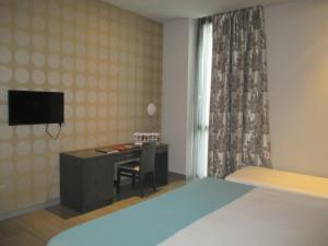 蓬费拉达Hotel Ciudad De Ponferrada的一间卧室配有书桌、一张床和一台电视。