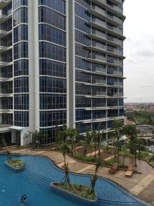 雅加达温莎招牌公寓的享有大型建筑和棕榈树游泳池的景色