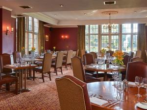 利明顿Macdonald Elmers Court Hotel的用餐室设有桌椅和窗户。