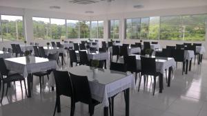 GuarabiraFrance Hotel的一间设有白色桌椅和窗户的用餐室