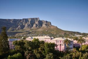 开普敦Mount Nelson, A Belmond Hotel, Cape Town的一座粉红色的建筑,背景是一座山