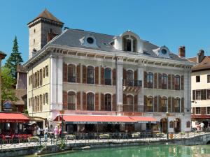 安锡Le Loft d'Annecy - Vision Luxe的一座大建筑,位于一座建筑前,毗邻一条河流