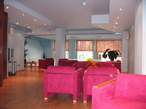 萨莫拉多纳沃卡酒店的客厅配有粉红色的椅子和桌子