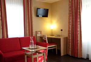 佩格尼茨Hotel Rosenhof Garni的酒店客房配有红色的沙发和书桌