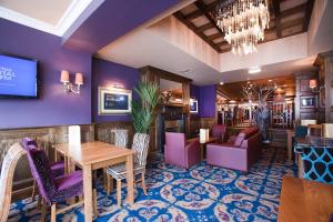 爱丁堡薇希尔斯波恩白女士酒店的餐厅拥有紫色的墙壁和桌椅