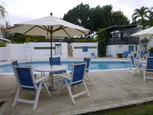 布里奇敦Rockley Golf Club, 2 bed 2 bath Pool, Tennis, Golf, Bar & Restaurant!的游泳池旁配有遮阳伞的桌椅