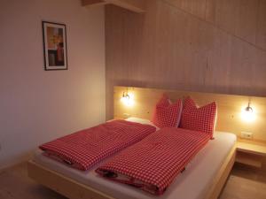 瓦尔道拉Liebharterhof的卧室配有红色和白色的床和红色枕头