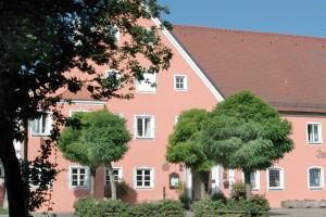 多瑙河畔诺伊堡祖斯特博瑞罗曼蒂克酒店的前面有树木的粉红色建筑