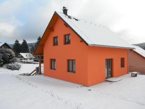 卡什佩尔斯凯霍里尤费赛璐度假屋的一座橘色房子,地面上积雪