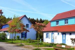 德兰斯克Ferienwohnung Bakenberg auf Rügen (So)的白色的房子,有红色的屋顶和长凳