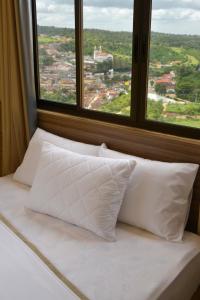 巴纳内拉斯Pousada Da Serra的窗户前的一张带白色枕头的床