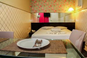 累西腓恩里克·迪亚斯（仅限成人）情趣酒店和汽车旅馆的一间房间,在玻璃桌上摆放着床和盘子