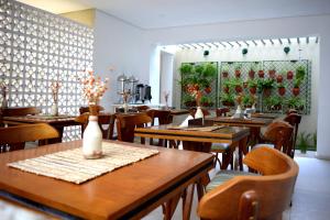 累西腓Pousada Lorde Inglês的餐厅设有木桌和椅子,种有植物
