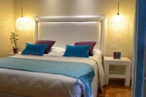 钱皮诺别墅套房酒店的一间卧室配有一张大床,提供蓝色和紫色枕头