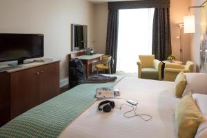 谢菲尔德谢菲尔德圣保罗Spa美居酒店的酒店客房设有一张配有电视和耳机的床。