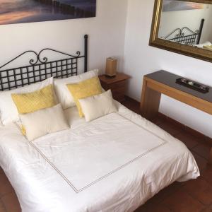 蓬塔穆赫雷斯Las Rosas Apartment (Adults Only)的一张带黄色枕头和镜子的白色床