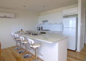 Emu Bay鸸鹋湾埃拉诺拉宁谧度假屋的厨房配有带凳子的柜台和冰箱。