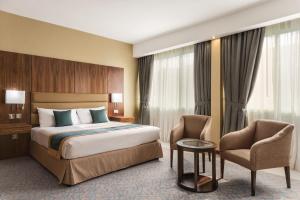 阿布扎比Howard Johnson by Wyndham Abu Dhabi Downtown的配有一张床和一把椅子的酒店客房