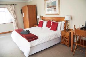 比勒陀利亚布鲁克林旅馆的卧室配有带红色枕头的大型白色床