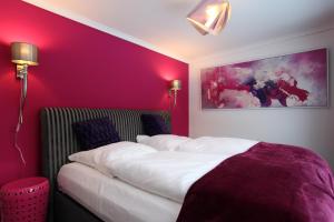 BasthorstKunst Pension Frahm的一间卧室设有紫色的墙壁和一张铺有白色床单的床。
