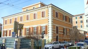 安科纳Hotel della Vittoria的一座大型砖砌建筑,前面有汽车停放
