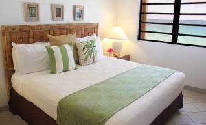 Meads Bay卡里玛尔海滩俱乐部 的一间卧室配有一张带绿色和白色枕头的大床