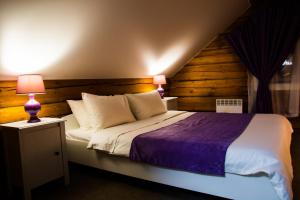 伊尔库茨克毕瑞兹卡宾馆的一间卧室配有一张大床和紫色毯子