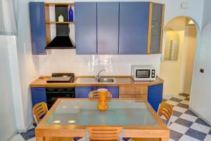 贾迪尼-纳克索斯Apartment Tysandros的厨房配有蓝色橱柜和一张带花瓶的桌子