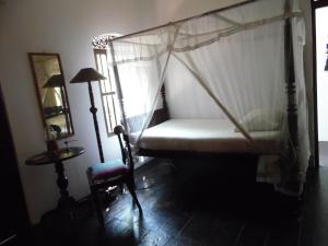 乌纳瓦图纳美梦之家旅馆的一间卧室配有一张天蓬床和一把椅子