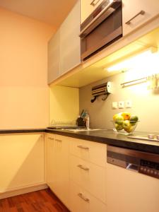 布拉迪斯拉发城市中心公寓的厨房配有白色橱柜,柜台上放着一碗水果
