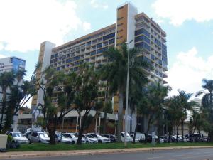 巴西利亚IKA Apart Hotel的停车场内有车辆停放的高楼