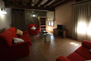 Villar de Plasencia萨尔瓦多林孔德尔比利亚尔酒店的客厅配有2张红色沙发和1台电视