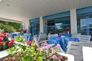 里乔内Hotel Rosalba的庭院设有蓝色的桌子和白色的椅子及鲜花