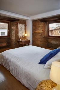 Janeiro de CimaCasa De Janeiro的卧室配有一张白色大床和石墙