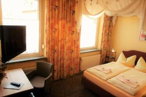 德利茨希格鲁奈灵德潘森酒店的一间卧室配有一张床、一张书桌和一台电视