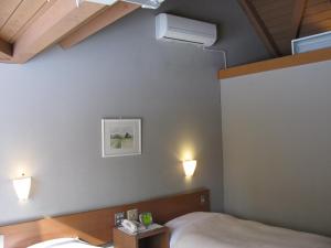 轻井泽轻井泽町山林小屋的卧室配有一张床,墙上有两盏灯