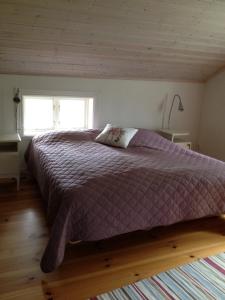韦纳穆斯图加林恩那不勒坦度假屋的一间卧室配有一张带紫色棉被的床和窗户。