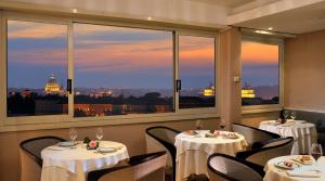 罗马贝斯特韦斯特皮卡迪利酒店的一间设有两张桌子的餐厅,享有城市美景