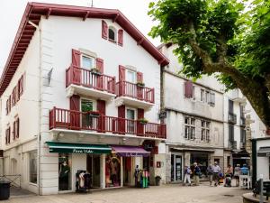 圣让-德吕兹Hotel Les Almadies - Coeur de Ville的白色的建筑,在街上设有红色的阳台