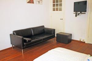 鹿特丹瓦尔恩贝格住宿加早餐酒店的客厅设有一张黑色皮沙发,配有电视