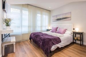 马德里Puerta Del Sol 3WC的一间卧室配有一张带紫色毯子的床