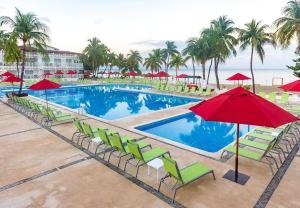 蒙特鲁伊斯英迪戈得可麦仑皇家酒店 - 全包的一个带绿色椅子和红色遮阳伞的游泳池