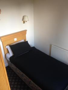 利兹麦内阿姆斯宾馆的一间卧室配有一张带黑色床单和一盏灯的床。